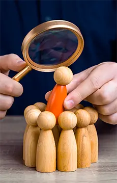 Person watching a human-figured toy through magnifying glass.